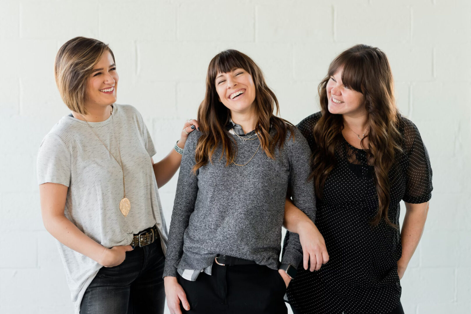 Three women smiling and enjoying each other's company indoors.